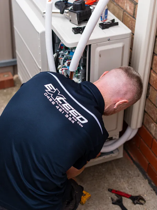 Technician servicing the inside of an outdoor air conditioning unit